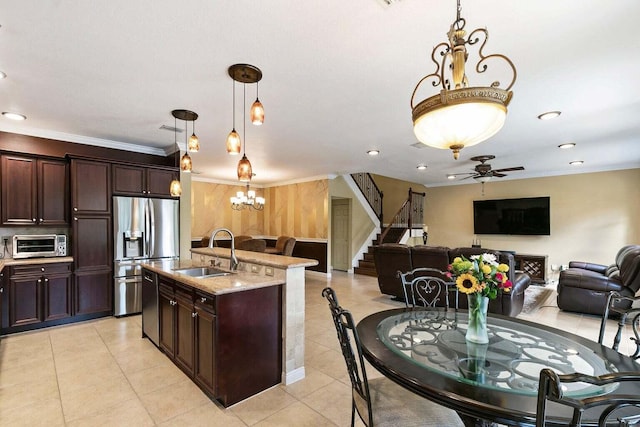 kitchen featuring light stone countertops, sink, stainless steel fridge, pendant lighting, and ceiling fan with notable chandelier