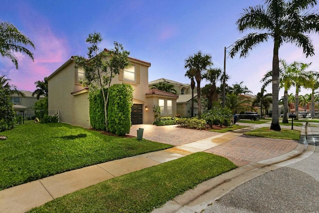 mediterranean / spanish house featuring a garage and a lawn