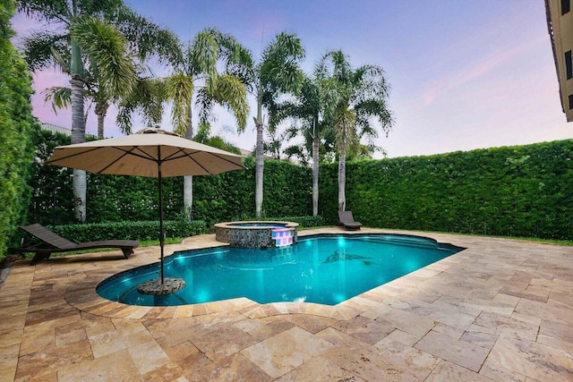 pool at dusk with an in ground hot tub and a patio