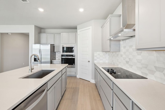 kitchen with sink, backsplash, stainless steel appliances, and wall chimney exhaust hood