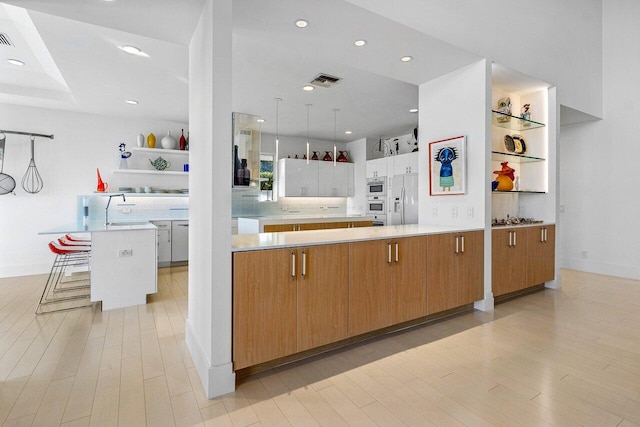 kitchen with pendant lighting, a large island, white fridge with ice dispenser, white cabinets, and a kitchen breakfast bar