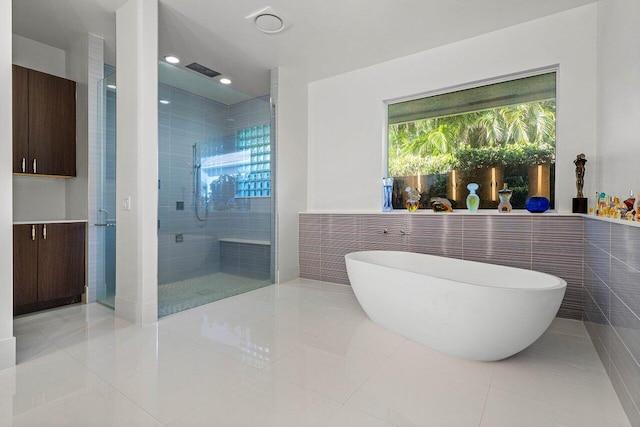 bathroom with tile walls, tile patterned flooring, and shower with separate bathtub