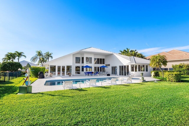 back of property featuring a patio, a fenced in pool, and a lawn