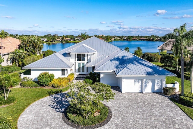 view of front of home with french doors, a front yard, a garage, and a water view