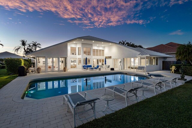 pool at dusk featuring a patio