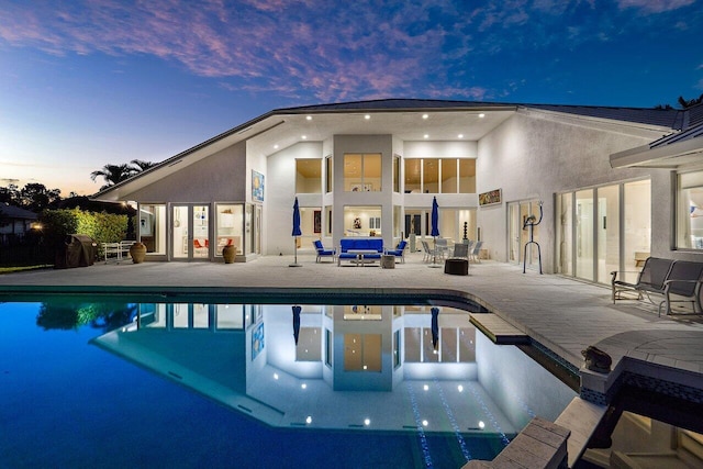 pool at dusk with a patio area and an outdoor living space