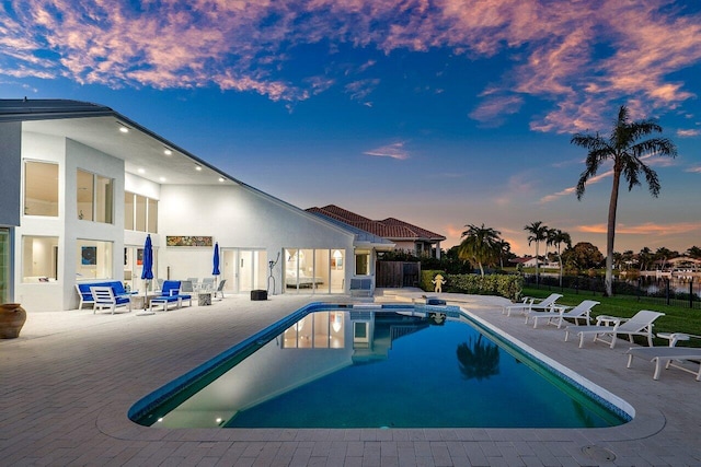 pool at dusk with a patio area