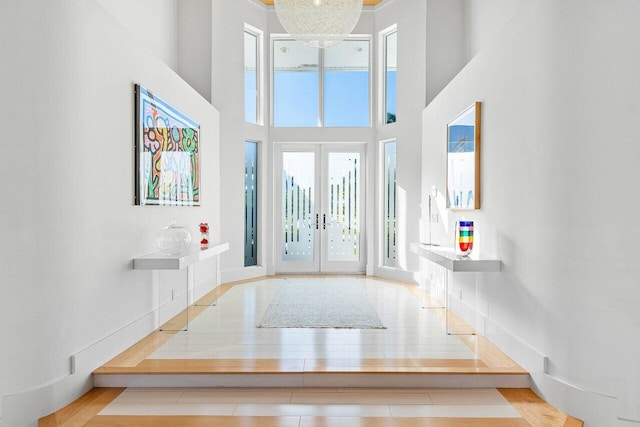 entrance foyer with a towering ceiling, french doors, and a notable chandelier