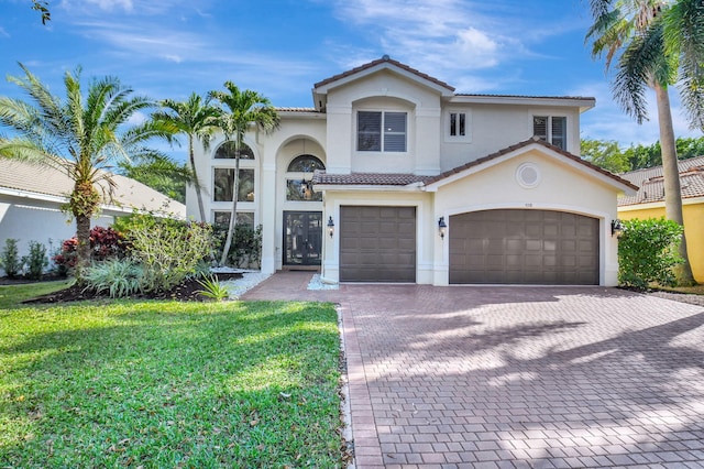 mediterranean / spanish home with a garage and a front lawn