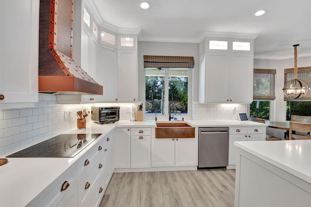 kitchen featuring black electric stovetop, white cabinets, stainless steel dishwasher, wall chimney exhaust hood, and decorative light fixtures