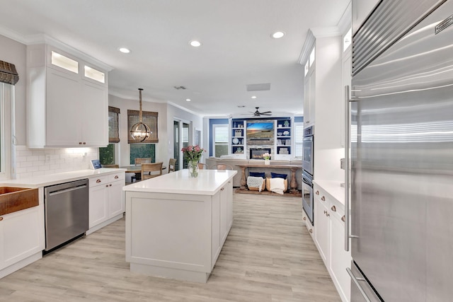 kitchen featuring tasteful backsplash, ceiling fan with notable chandelier, stainless steel appliances, decorative light fixtures, and white cabinetry