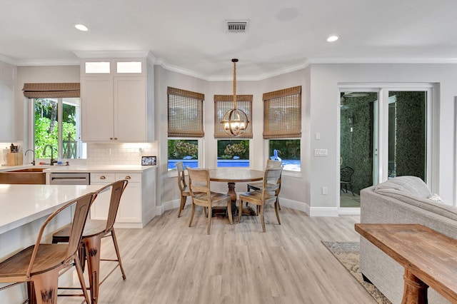 dining space with light hardwood / wood-style flooring, an inviting chandelier, ornamental molding, and sink