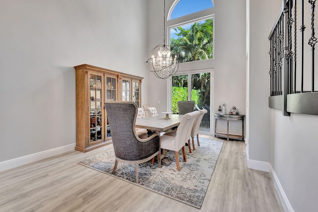 dining space featuring a high ceiling, light wood-type flooring, and an inviting chandelier