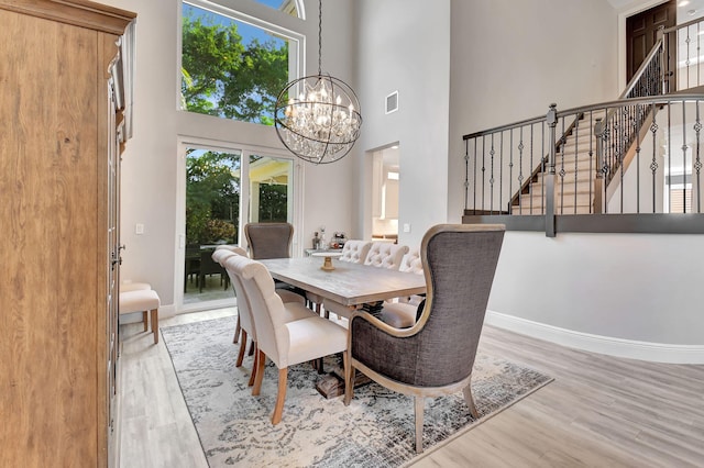 dining space with a high ceiling, light wood-type flooring, and an inviting chandelier