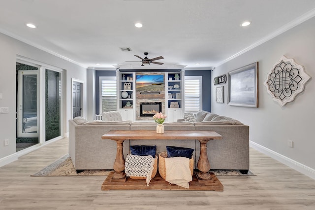 living room featuring a fireplace, ceiling fan, light hardwood / wood-style flooring, and ornamental molding