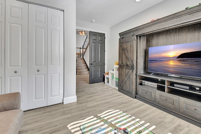 unfurnished living room with a barn door and light hardwood / wood-style floors