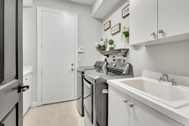 laundry room with cabinets, light tile patterned floors, washer and clothes dryer, and sink