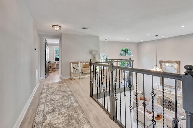 hallway featuring light hardwood / wood-style floors and a notable chandelier