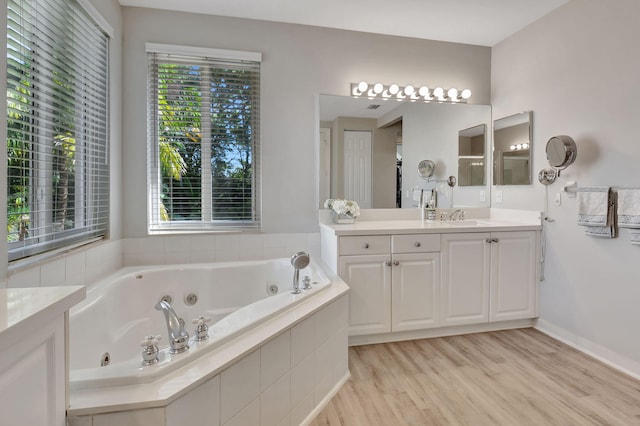 bathroom with hardwood / wood-style floors, vanity, and tiled tub