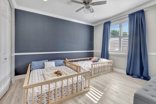 bedroom featuring a closet, ceiling fan, crown molding, and light hardwood / wood-style floors