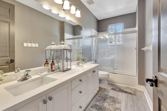 full bathroom featuring vanity, toilet, wood-type flooring, and enclosed tub / shower combo