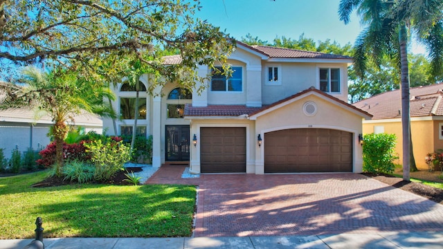 mediterranean / spanish home featuring a garage and a front lawn