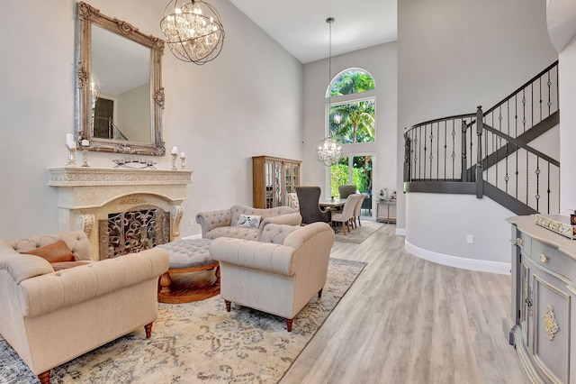 living room featuring a towering ceiling, a premium fireplace, a wealth of natural light, and light hardwood / wood-style flooring