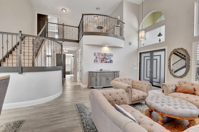 living room with a wealth of natural light, a towering ceiling, and light hardwood / wood-style floors