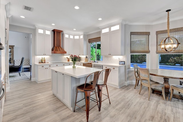 kitchen featuring a chandelier, white cabinetry, hanging light fixtures, and wall chimney range hood