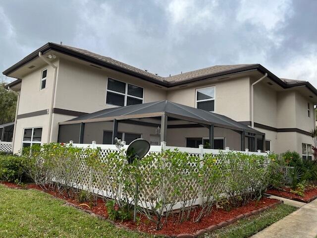 rear view of property with glass enclosure and stucco siding