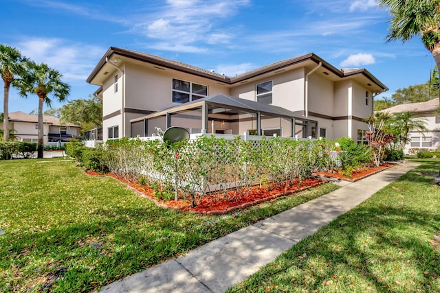 view of side of property featuring a lanai, a lawn, and stucco siding