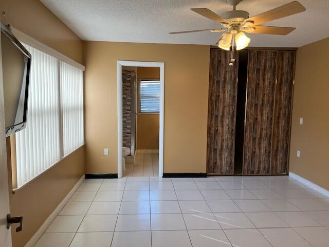 18 Amherst Ct Unit B, Royal Palm Beach, FL 33411 - tiled empty room with a ceiling fan, a textured ceiling, and baseboards
