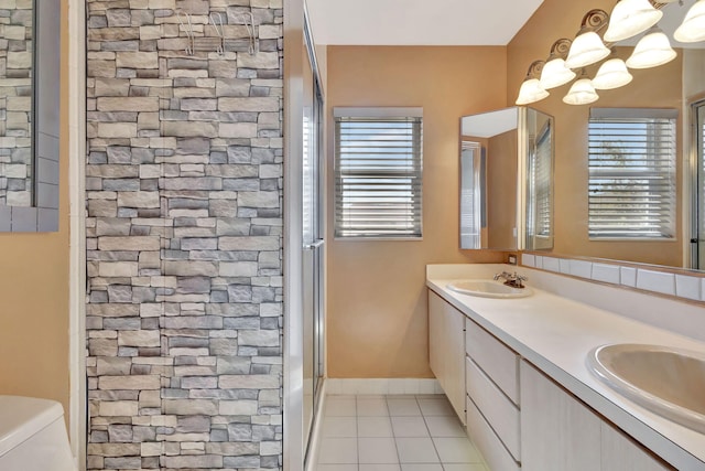 full bathroom with toilet, double vanity, a sink, and tile patterned floors