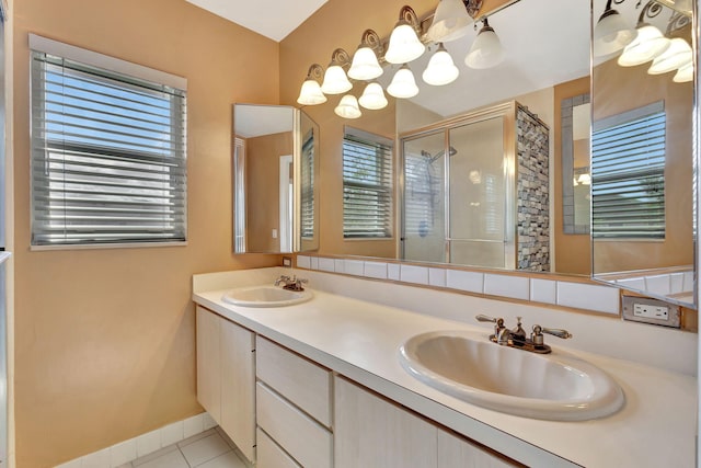 bathroom with double vanity, a shower stall, a sink, and tile patterned floors