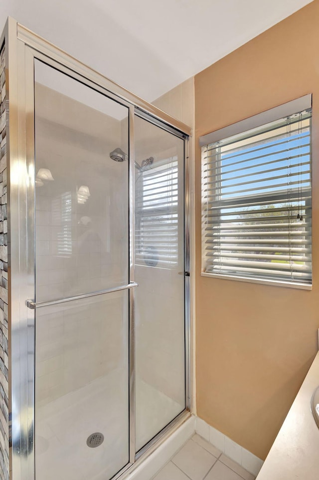 full bathroom featuring vanity, baseboards, tiled shower, and tile patterned floors