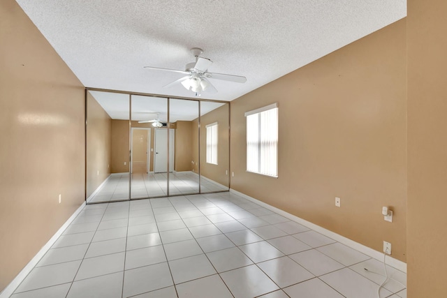 unfurnished bedroom with ceiling fan, a textured ceiling, baseboards, and light tile patterned floors