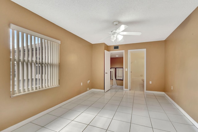 unfurnished bedroom with light tile patterned floors, visible vents, a ceiling fan, a textured ceiling, and baseboards