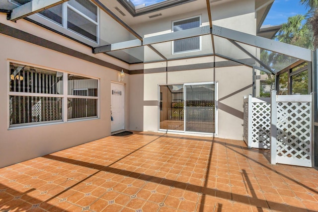 view of patio with glass enclosure and visible vents