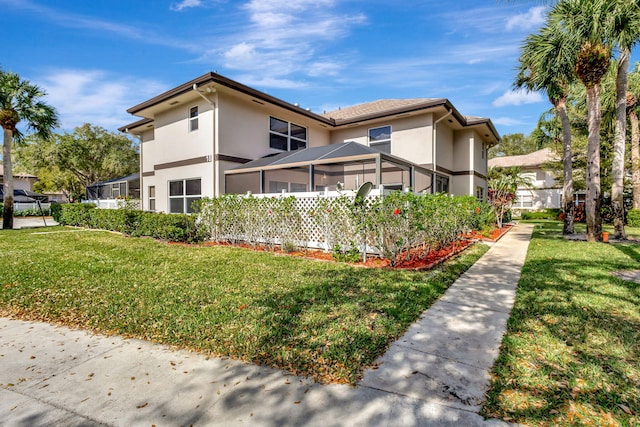 view of property exterior featuring glass enclosure, a lawn, and stucco siding