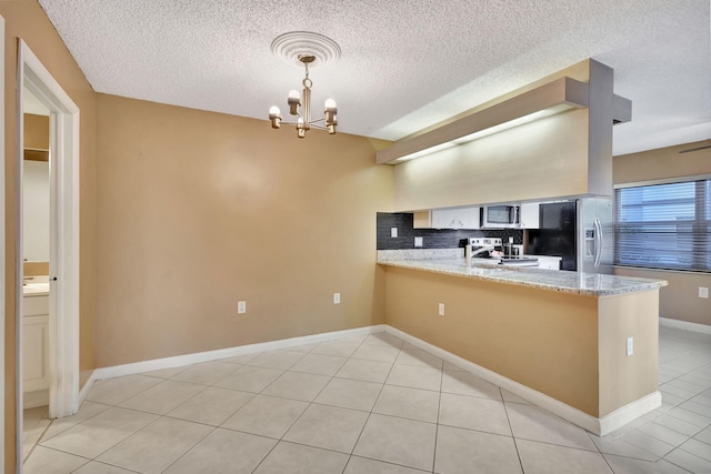 kitchen featuring a chandelier, a peninsula, appliances with stainless steel finishes, and light stone countertops