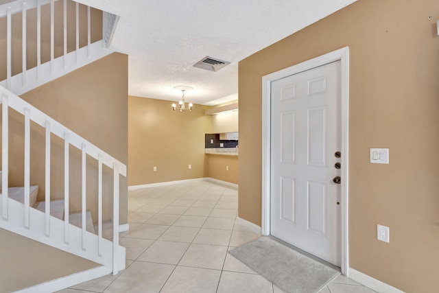 entryway with light tile patterned floors, a textured ceiling, stairs, and visible vents