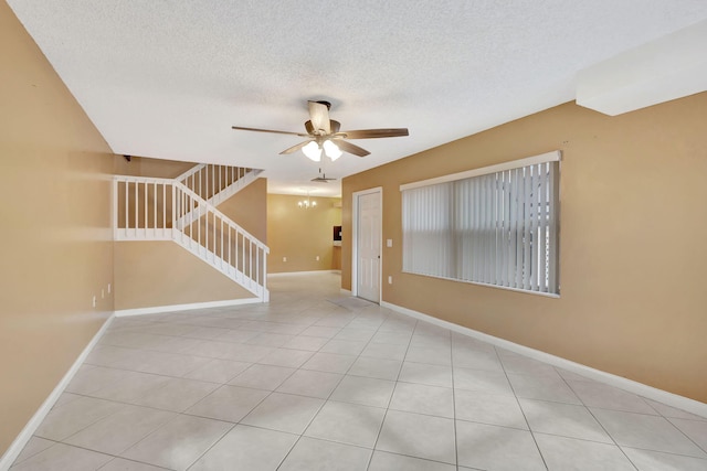 spare room featuring stairs, ceiling fan, a textured ceiling, and baseboards