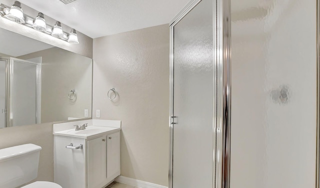 bathroom with a textured ceiling, vanity, toilet, and an enclosed shower