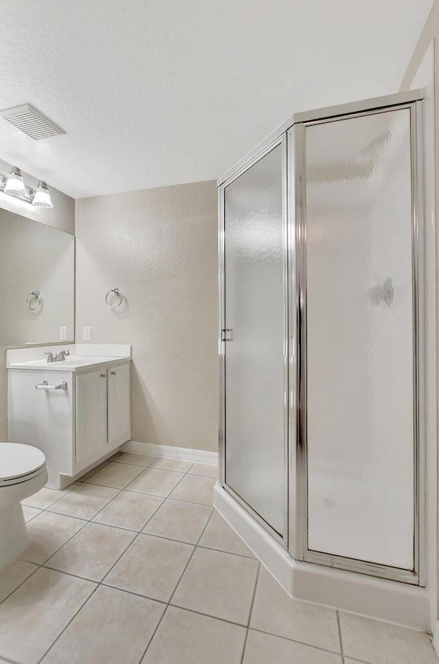 bathroom with tile patterned floors, vanity, toilet, and a shower with door