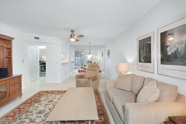 living room featuring ceiling fan, light tile patterned flooring, and a textured ceiling