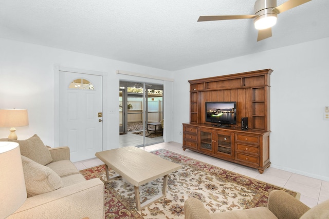 living room with ceiling fan, a textured ceiling, and light tile patterned floors