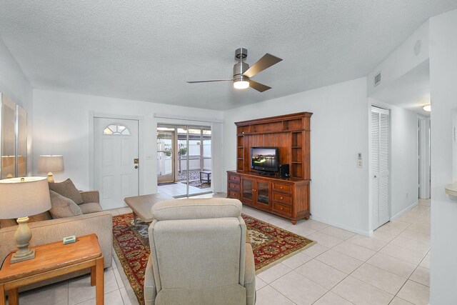 tiled living room with a textured ceiling and ceiling fan