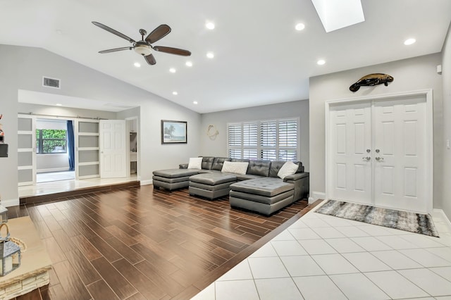 living room with lofted ceiling with skylight, ceiling fan, and plenty of natural light