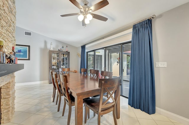 dining room featuring ceiling fan, light tile patterned flooring, lofted ceiling, and a fireplace