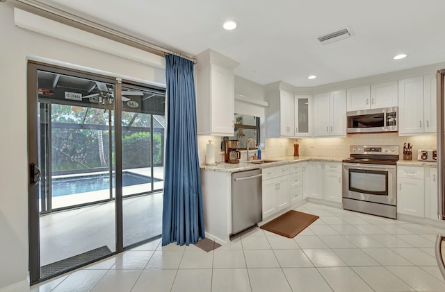 kitchen with appliances with stainless steel finishes, tasteful backsplash, white cabinetry, and sink